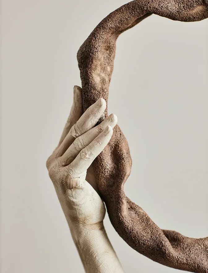 Sculpture of two intertwined hands in stone and bronze