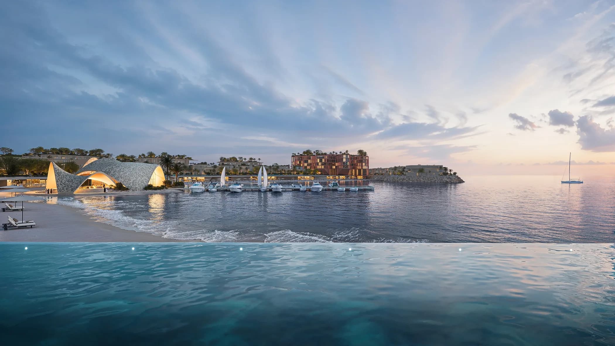 The Mira Coral Bay marina and beach club across calm water at dusk